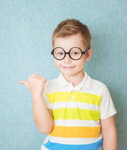 Portrait of stylish little boy with finger finger at points in side. Kid on blue blackboard. Success, bright idea, creative ideas and innovation technology concept