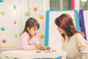 Mother and daughter sitting in a playroom, playing a ludo game and enjoying their time together