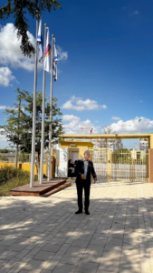 נשיא המכללה נואם ברחבת הכניסה של האקדמית חמדת לצד דגלי ישראל והמכללה.